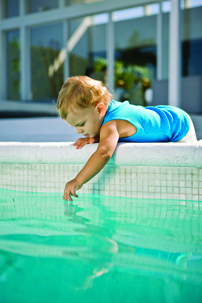 Baby reaching into pool